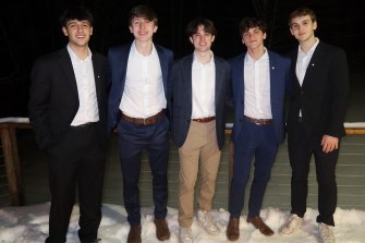 Five students wearing white button downs and blazers standing next to each other.