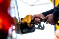 A person using two hands to pump gas into their car. All that's visible is their hands, not the rest of their body.