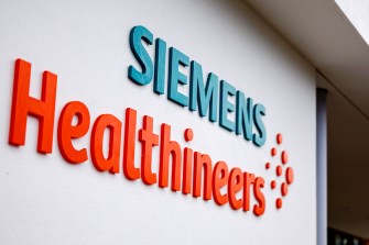 'Siemens Healthineers' name on a wall with 'Siemens' in blue and 'Healthineers' in orange.