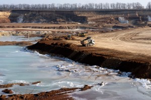 A truck parked on the edge of an ilmenite open pit mine in a canyon.