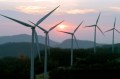 Five wind turbines on a hill with a sunset behind them.