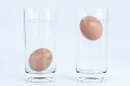 Two glasses of water next to each other, one with an egg at the bottom of the glass, the other with the egg floating at the top.