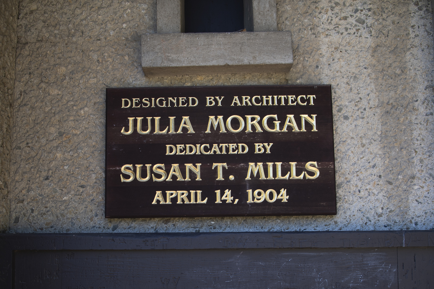 A plaque that says 'Designed by architect Julia Morgan. Dedicated by Susan T. Mills April 14, 1904'. 