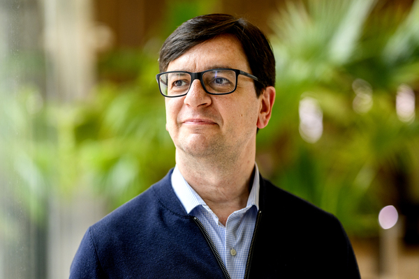 Estaban Moro, a professor in the Network Science Institute, poses for a portrait against a green background.