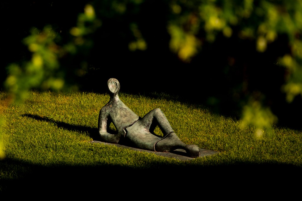 A sculpture that looks like a man laying on a hill propped up by one elbow on the Boston campus.