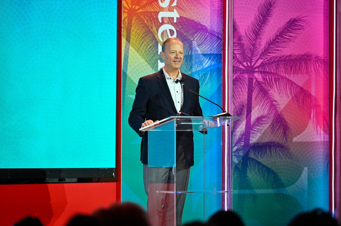 A speaker standing at a clear podium on stage at the Global Leadership Summit. 