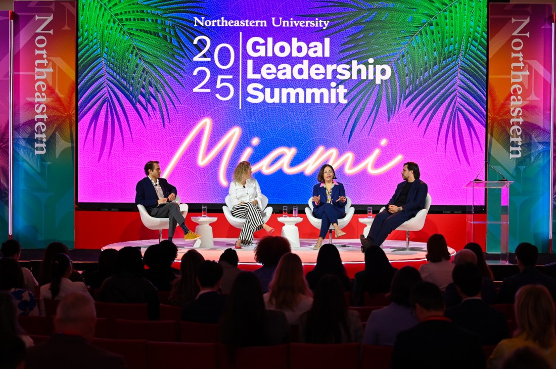 Four speakers sitting in white chairs on stage in front of a screen that says 'Northeastern University 2025 Global Leadership Summit' on it.