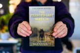 A person holding up a copy of The Prendergast Watch. The cover has the title on it at the top in yellow all caps font. At the bottom is Emma Woodhouse&#039; name in all caps white text. A victorian coach on a road is depicted at the center of the cover.