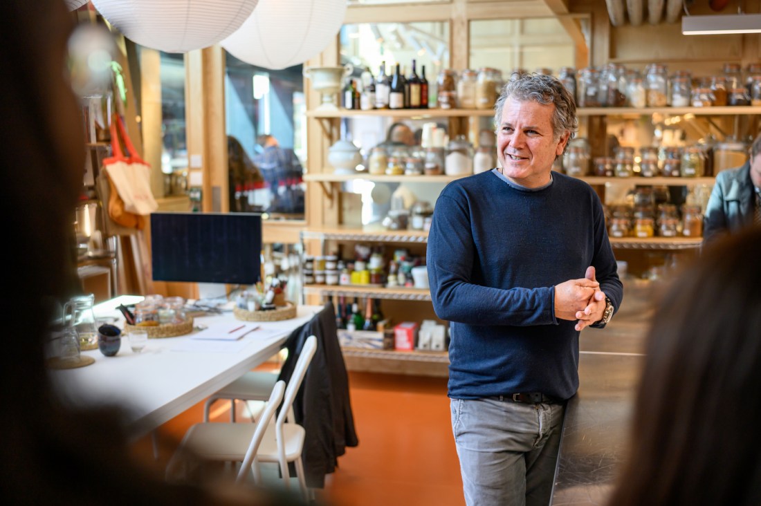 A person wearing grey jeans and a blue sweater in a bakery chain headquarters.