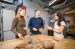 Three people standing around a table in a bakery headquarters.