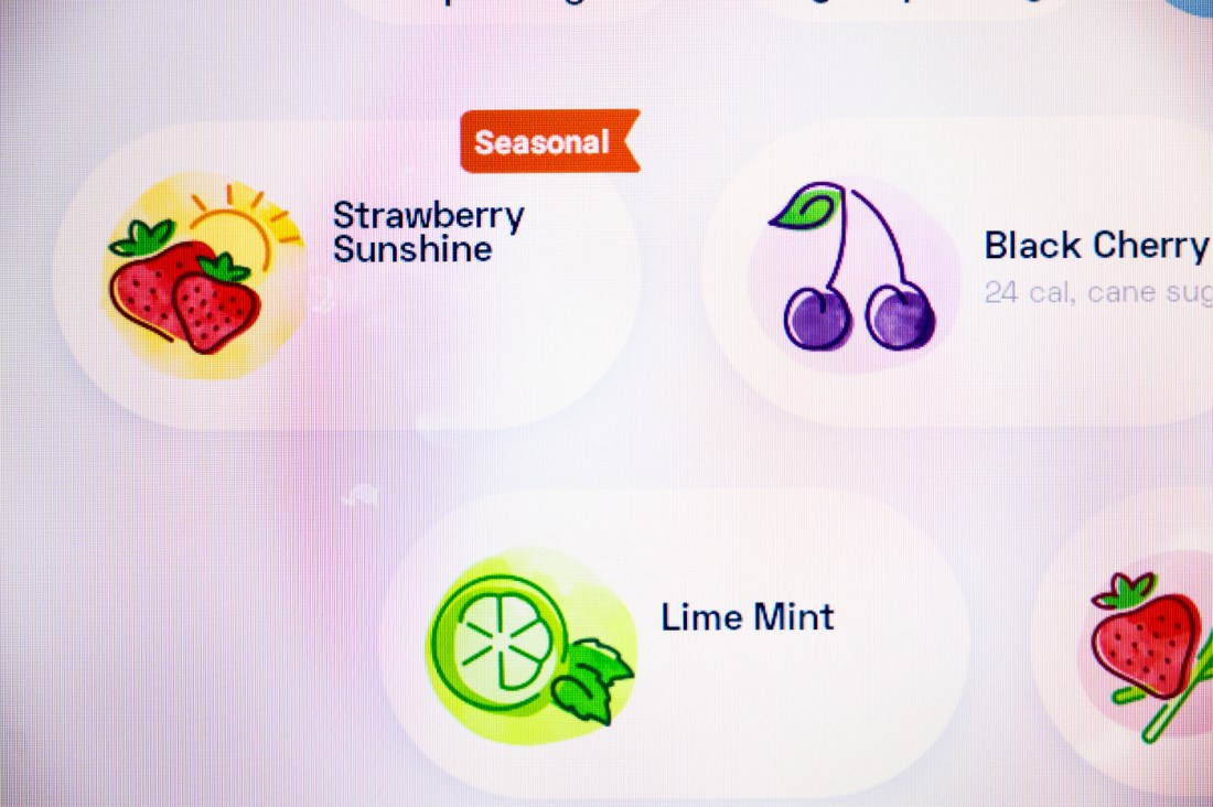 The screen on the Bevi machine displaying several flavors of water, including 'Strawberry Sunshine,' 'Black Cherry,' and 'Lime Mint'.