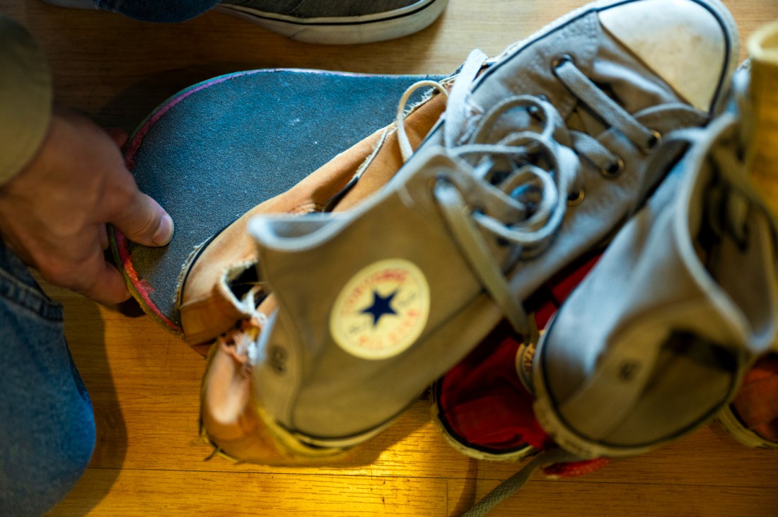 Two pairs of converse shoes stacked on top of a skateboard. 