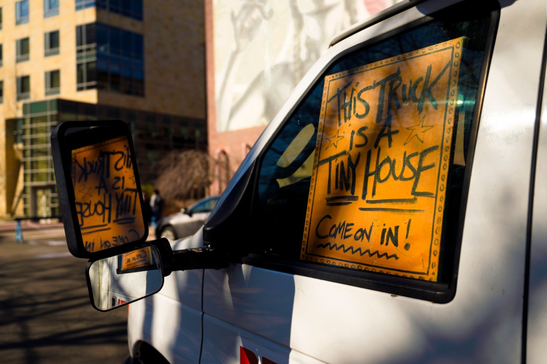 The cab of a white U-Haul truck with a yellow sign on the inside of the window.