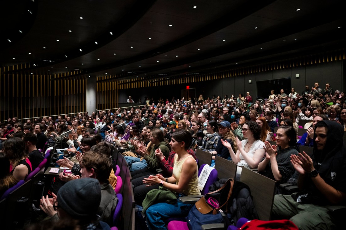 An auditorium packed with students clapping.