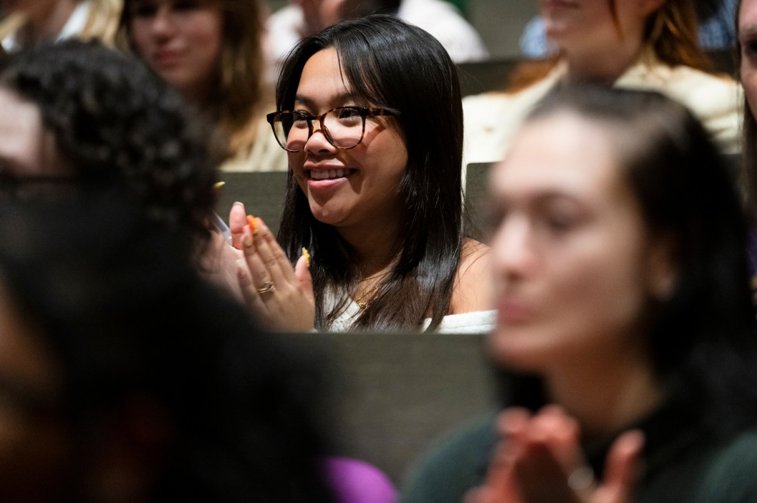 A student sitting in the audience clapping for Alison Bechdel.