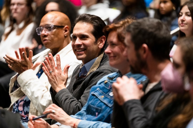 Audience members smiling and clapping.