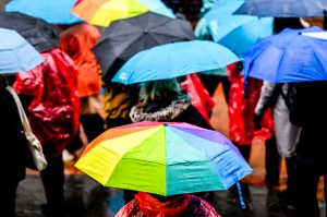 A group of people walks outside under colorful umbrellas on a rainy day.