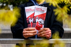 A student holding two SGA campus guide pamphlets.
