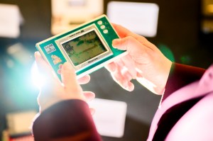 Adriana De Souza E Silva playing a rectangular turquoise colored gaming device.