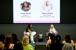Two people are on stage speaking to an audience.