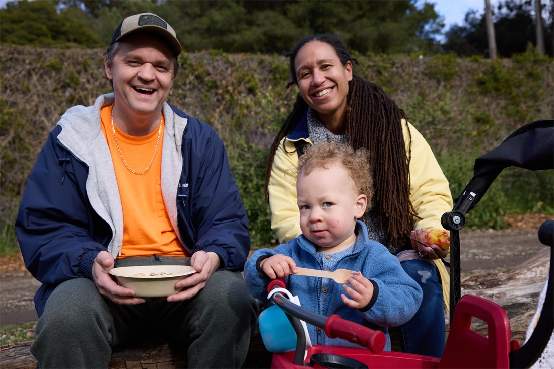 Two adults and a child sitting together smiling.