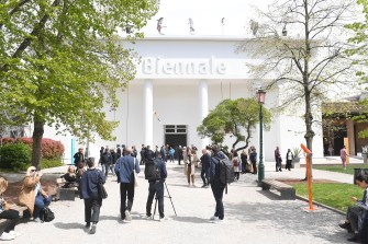 Visitors walking in front of a building that says 'Biennale' on it.