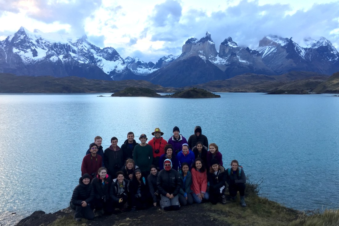 A group photo of the Dialogue of Civilization members. Everyone is bundled up. In the background is a lake and in the far background is the Patagonia mountain range, snow-capped.