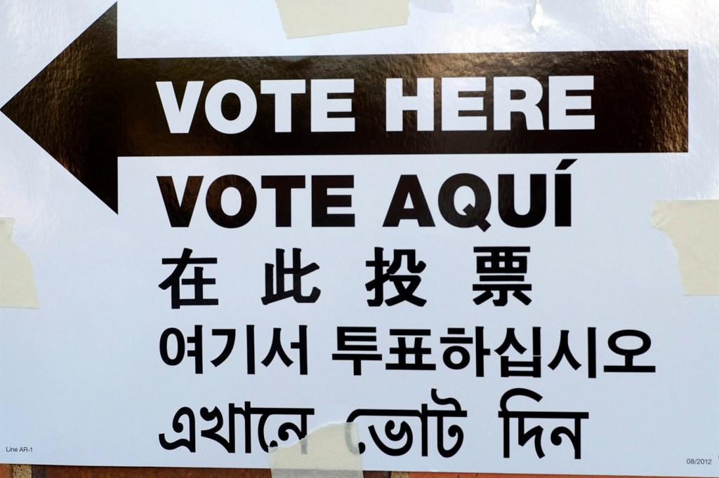 A sign that says 'Vote Here' in five different languages; English, Spanish, Chinese, Korean, and Bengali.