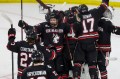 Northeastern hockey players cheering together on the ice.