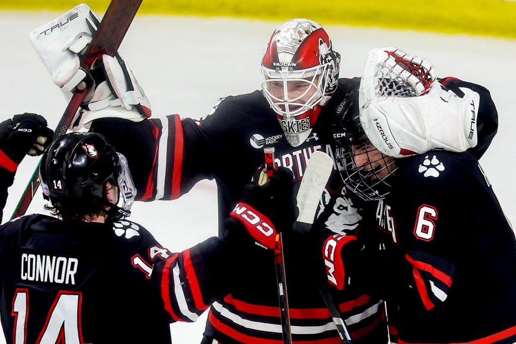 Northeastern hockey players cheering with each other on the ice.