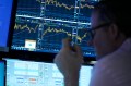 A person working on the floor at the NY Stock Exchange looking at screens displaying graphs.