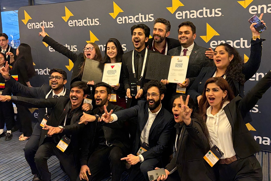 A group of people posing for a photo together in front of a backdrop with the brand name 'enactus' on it.