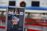 A sign in an airport that says &#039;Real ID&#039; on it with a person holding a drivers license card.