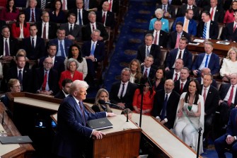 President Donald Trump standing in front of a microphone at the front of a joint session in Congress.