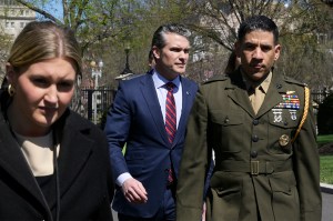 Pete Hesgeth walking outside in the sun.