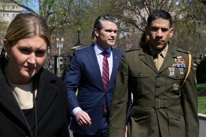 Pete Hesgeth walking outside in the sun.