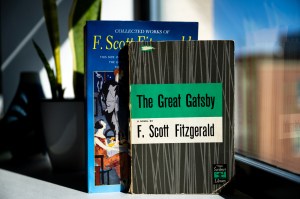Two copies of The Great Gatsby with different covers standing up on a table.