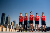 Five Northeastern student athletes posing in front of the Boston skyline.