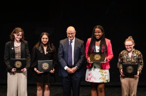 Students stand on either side of Northeastern's President Aoun at the Academic Honors Convocation.