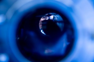 Kin Chung Fong looking through a microscope, seen through a tube.