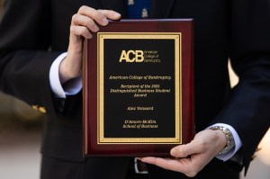 Alex Voissard holding an award plaque.