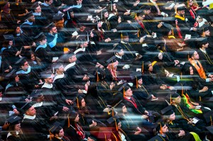 Graduates in caps and gowns sit in rows during a commencement ceremony.