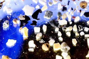 Microplastics spread out on a reflective surface in a lab.