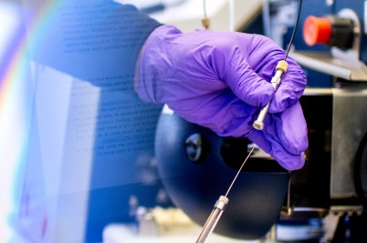 Jeffrey Agar's hand in a purple glove holding a piece of lab equipment.