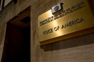 A gold sign on a building that says 'Voice of America' on it.