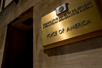 A gold sign on a building that says 'Voice of America' on it.