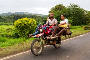 Three people riding a rigged up motorcycle in the Philippines.