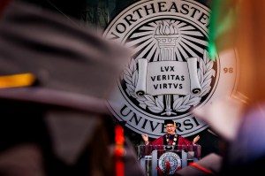 Northeastern President Joseph Aoun speaks at the 2025 Commencement ceremony in front of the university seal.