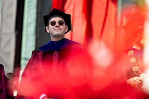 Elliot Grainge stands on stage in academic regalia during Northeastern’s 2025 Commencement at Fenway Park.