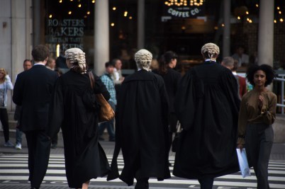 Lawyers walking into the Royal Court of Justice wearing wigs.